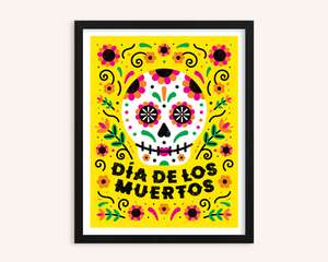 Framed artwork with a colorful sugar skull design and 'Dáa de los Muertos' text on a yellow background.