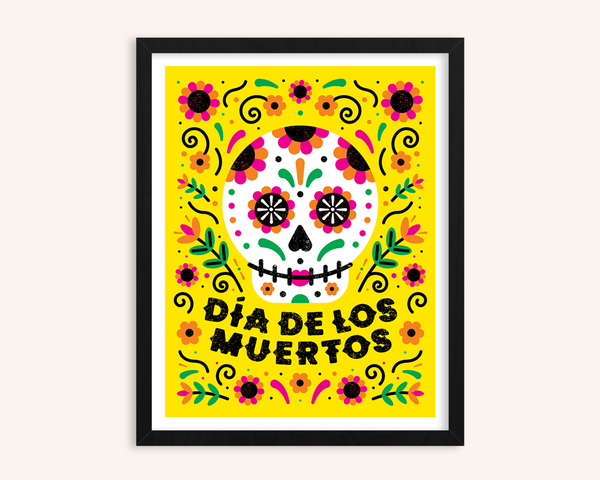 Framed artwork with a colorful sugar skull design and 'Dáa de los Muertos' text on a yellow background.