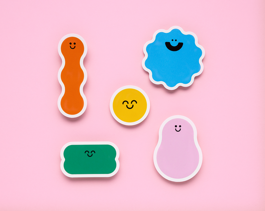 Set of colorful, smiley-faced stickers on a pink background