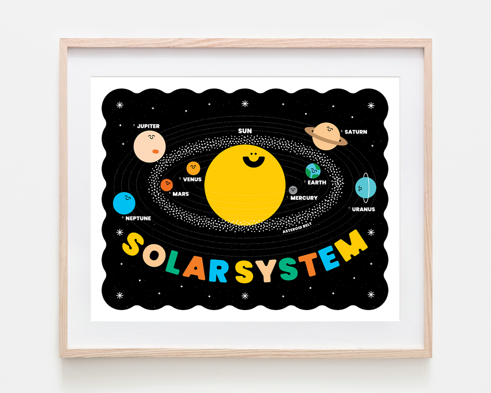A framed children's educational poster of the Solar System, featuring a cute cartoon sun, planets, and the word 'SOLARSYSTEM' in colorful letters on a black background, housed in a light wood frame.
