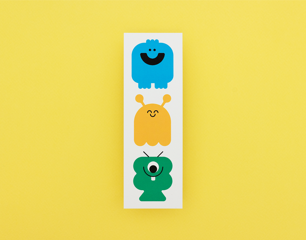 Three colorful monster bookmark on a white card against a yellow background