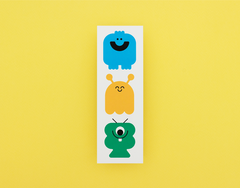 Three colorful monster bookmark on a white card against a yellow background
